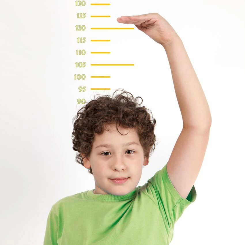 Boy with green shirt and hand above head on height scale