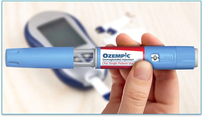 Hand holding Ozempic (semaglutide) Injection pen with glucose monitoring machine on table