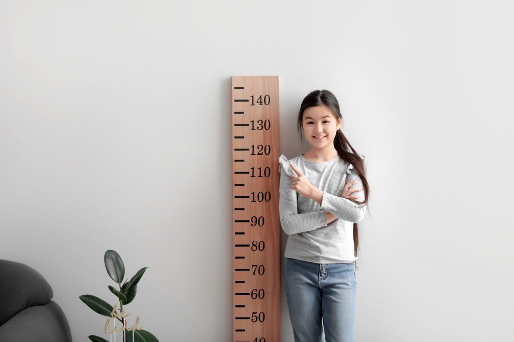 Does HGH Make you Taller Girl pointing at Height Chart